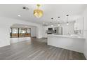 Open-concept kitchen and living area with hardwood floors, pendant lighting, and stainless steel appliances at 7331 Blue Jacket W Pl, Winter Park, FL 32792