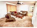 Cozy living room featuring plush carpeting, comfortable seating, and a classic ceiling fan at 8547 Cedar Cove Dr, Orlando, FL 32819