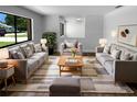 Bright living room featuring two plush gray sofas, arm chair, ottoman, and a large window with views of the outdoors at 9744 Tattersall Ave, Orlando, FL 32817