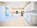 Modern kitchen featuring white cabinetry, stainless steel appliances, and a large island with seating at 1023 Sugarwood St, Davenport, FL 33837