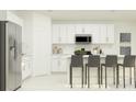 Modern kitchen featuring white cabinetry, stainless steel appliances, and a breakfast bar with seating at 2125 Lasso Loop, Eagle Lake, FL 33839