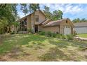 Charming tan home featuring a stone facade, large windows, mature landscaping, and an attached garage at 25438 Pine Valley Dr, Sorrento, FL 32776