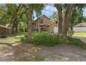 Charming tan home featuring a stone facade, large windows, mature landscaping, and an attached garage at 25438 Pine Valley Dr, Sorrento, FL 32776