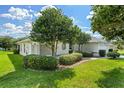 Well-maintained house exterior featuring lush green lawn, beautiful trees, and manicured landscaping at 26908 Honeymoon Ave, Leesburg, FL 34748