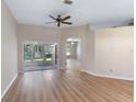 Spacious living room featuring light wood floors, a ceiling fan, and sliding glass doors to the patio at 26908 Honeymoon Ave, Leesburg, FL 34748