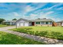 Single-story house with a well-maintained lawn and a three-car garage, featuring a red front door at 3024 Saratoga Dr, Orlando, FL 32806