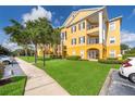 Yellow apartment building with well-kept lawn, sidewalk, and black wrought iron balcony railings at 3707 Conroy Rd # 1715, Orlando, FL 32839