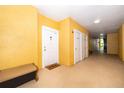 Apartment hallway showing neutral paint, three unit entrance doors, and a bench at 3707 Conroy Rd # 1715, Orlando, FL 32839