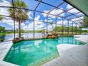 Screened-in pool offers a beautiful waterfront view, a rock waterfall feature, and an inviting space for leisure at 3728 Hunters Isle Dr, Orlando, FL 32837