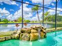 Tranquil pool featuring a charming rock waterfall and serene lake view, creating a relaxing oasis at 3728 Hunters Isle Dr, Orlando, FL 32837