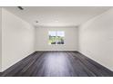 Spacious living room with wood-look flooring, neutral walls, and a large window for ample natural light at 5242 Scrub Mint Ln, Apopka, FL 32712
