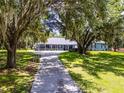 Picturesque single-story home with a covered front porch and driveway, framed by majestic, moss-draped oak trees at 9642 Florida Boys Ranch Rd, Clermont, FL 34711