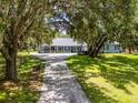 Stunning single-story home with a covered front porch, surrounded by mature trees and a well-manicured lawn at 9642 Florida Boys Ranch Rd, Clermont, FL 34711