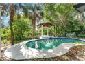 Backyard pool surrounded by lush landscaping and a covered gazebo at 1148 Northcrest Dr, Apopka, FL 32703