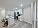 Modern kitchen featuring new stainless steel appliances, white cabinetry, breakfast bar, and wood-look flooring at 2592 Grassy Point Dr # 106, Lake Mary, FL 32746