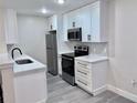 Well-lit kitchen features white cabinets, stainless steel appliances, sleek black hardware, and wood-look floors at 2592 Grassy Point Dr # 106, Lake Mary, FL 32746
