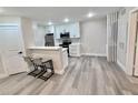 Modern kitchen featuring new stainless steel appliances, white cabinetry, breakfast bar, and wood-look flooring at 2592 Grassy Point Dr # 106, Lake Mary, FL 32746