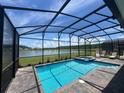 Screened-in pool and spa with tranquil lake views and a brick paver deck at 2855 Bookmark Dr, Kissimmee, FL 34746