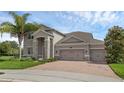 Attractive home features stone accents, a three-car garage, a brick driveway, and a well-manicured lawn at 32004 Redtail Reserve Blvd, Sorrento, FL 32776