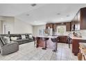Open-concept kitchen featuring dark wood cabinets, stainless steel appliances, a center island, and modern bar stools at 443 Magpie Ct, Poinciana, FL 34759
