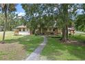 Charming home featuring a stone facade, mature trees, and a walkway leading to the entrance at 546 Winona Dr, Geneva, FL 32732