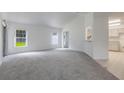 Open floor plan with new carpeting, windows providing natural light, and a view of the kitchen at 5990 Se 5Th Pl, Ocala, FL 34472