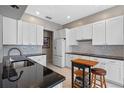 Modern kitchen featuring white cabinets, sleek black countertops, stainless steel appliances, and stylish backsplash tiles at 1225 Hollow Pine Dr, Oviedo, FL 32765