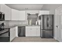 Contemporary kitchen boasting white cabinetry, granite countertops and sleek, stainless steel appliances at 12419 Eryn Ct, Clermont, FL 34711