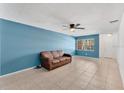 Inviting living room with blue walls, tile flooring, and a cozy brown leather sofa beneath a ceiling fan at 1288 Americana Pl, Orlando, FL 32807
