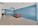 Inviting living room showcases tile floors, blue walls, a brown sofa, and a view of the adjacent dining area at 1288 Americana Pl, Orlando, FL 32807