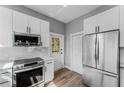 Modern kitchen boasts white cabinets, stainless steel appliances, and stylish wood-look flooring at 1480 Wauchula St, Intercession City, FL 33848