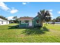 Quaint green house with a cozy front porch, complemented by a mature palm tree at 1519 Illinois Ave, St Cloud, FL 34769