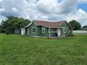 Green house with a covered porch and well-maintained lawn, showcasing a classic design at 1519 Illinois Ave, St Cloud, FL 34769