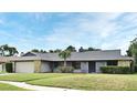 Charming single-story home with stone accents, a gray roof, green lawn, and a sidewalk to the front door at 173 Tollgate Br, Longwood, FL 32750