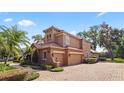 Side exterior featuring an attached three-car garage, lush landscaping, and a winding brick pathway at 1813 Glenbay Ct, Windermere, FL 34786