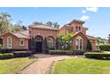 Stunning Mediterranean-style home with a red tile roof, arched entryway, and lush, mature landscaping at 1813 Glenbay Ct, Windermere, FL 34786