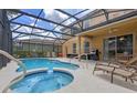 Inviting screened-in pool area with spa, lounge chairs, and an outdoor dining area, ideal for relaxation and gatherings at 5172 Oakbourne Ave, Davenport, FL 33837
