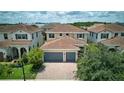 Two-story house showcasing red tile roof, green landscaping, and a brick driveway leading to a two-car garage at 10275 Henbury St, Orlando, FL 32832
