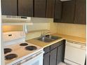 Classic kitchen featuring white appliances, a double sink, and dark cabinetry at 228 Everest Pt # 108, Casselberry, FL 32707