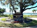 Community sign for Sweetwater Beach with lush landscaping and lake in the background at 2313 Park Village Pl, Apopka, FL 32712