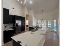 Modern kitchen with large island, stainless appliances, black cabinets, and views to pool at 2313 Park Village Pl, Apopka, FL 32712