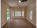 Open living room with wood floors, fan, sliding glass doors to the pool, and large windows at 2313 Park Village Pl, Apopka, FL 32712