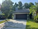 Exterior shot of a single-Gathering home featuring a two-car garage, mature trees, and landscaping at 304 Spring Run Cir, Longwood, FL 32779