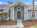 Home entrance featuring a classic door with sidelights, covered porch, and mature landscaping at 4274 Meeting Pl, Sanford, FL 32773