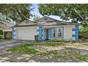 Inviting home featuring a two-car garage, blue trim, mature trees, and a well-maintained lawn at 4398 Fox Hollow Cir, Casselberry, FL 32707