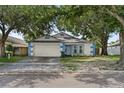 Attractive one-story home boasting blue trim, an attached garage, and shade trees at 4398 Fox Hollow Cir, Casselberry, FL 32707