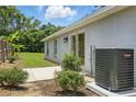 Exterior view of the side of the house with an AC unit and small yard with grass and bushes at 608 Swanson St, Groveland, FL 34736