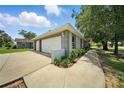 View of the detached garage and driveway featuring a two-car garage, landscaping, and exterior paint at 608 Swanson St, Groveland, FL 34736