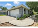View of the detached garage and driveway featuring a two-car garage, landscaping, and exterior paint at 608 Swanson St, Groveland, FL 34736