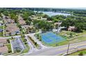 Community aerial view featuring tennis courts, lush greenery, and a serene lake backdrop at 750 Olympic Cir # D1, Ocoee, FL 34761
